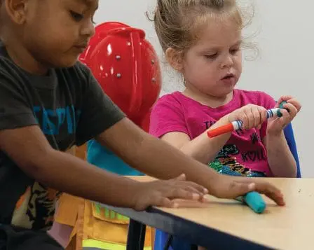 Children engaging in a hands-on activity at a table.