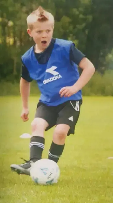 Mikey playing soccer in a blue bib.