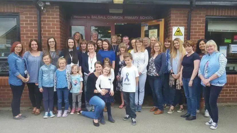 Children and adults pose for a photo outside Balsall Primary School for "Wearing Blue" day.