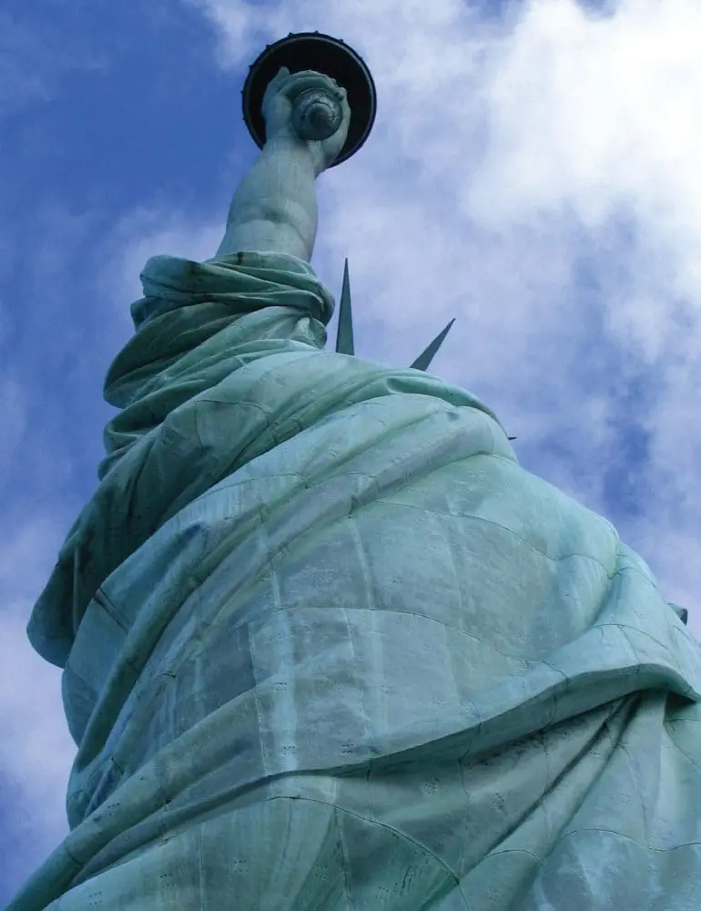 The Statue of Liberty from a low-angle view against a cloudy sky.
