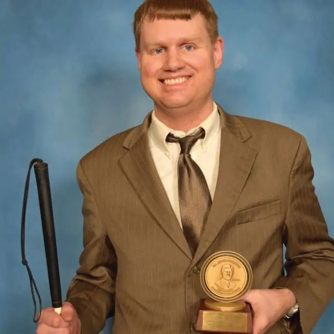 Ray McAllister holding a cane and a trophy.