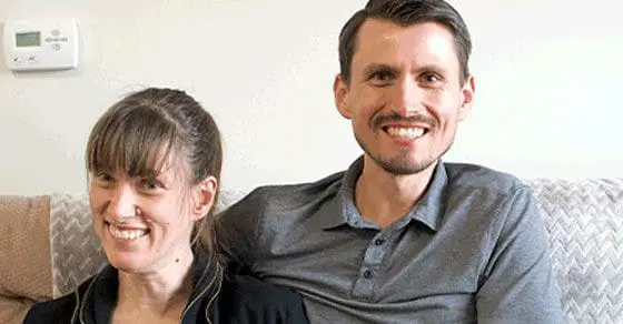 Sarah and Eric smiling at the camera while sitting on a couch.