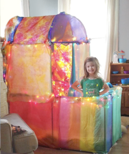 Young girl standing in a colorful fort decorated with lights