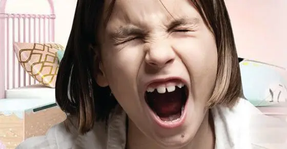 A child screams with eyes closed and mouth open wide.