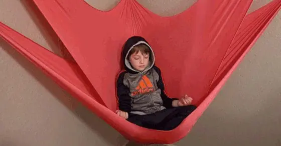 Boy sitting in a pink sensory swing.