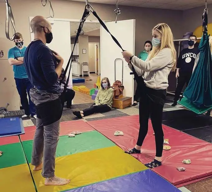 People in a sensory gym with hanging equipment and mats