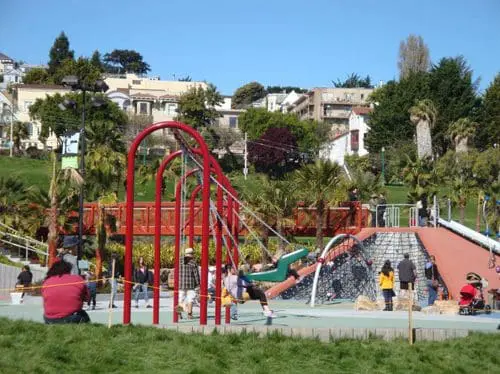 Helen Diller Playground with slides, swings, and climbing structures under a clear blue sky.