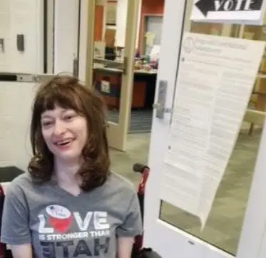 Brooke wearing a t-shirt that says "Love is stronger than hate" smiles.