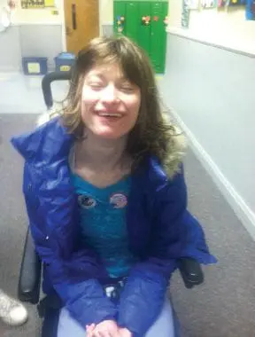 Brooke smiling while sitting in a wheelchair outdoors.