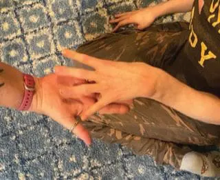 Brooke's hand being held as she touches another hand.