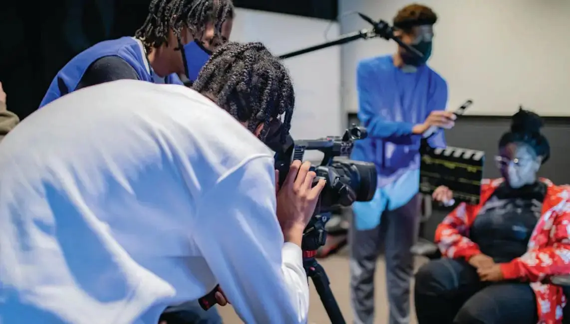 Three people in a room filming.
