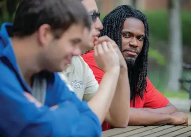 Three men sitting at a table outdoors.