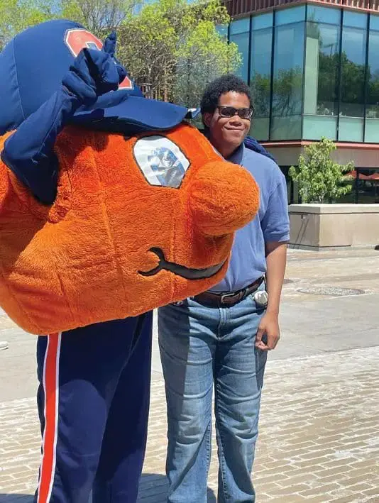 A person stands next to a mascot costume.