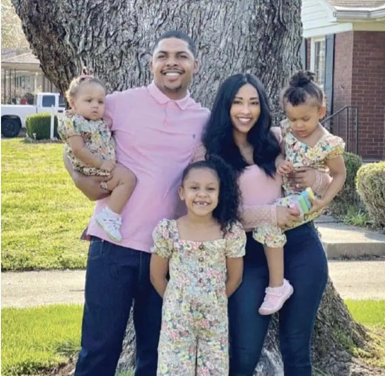 Indigo Abell and her family stand in front of a tree.
