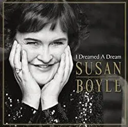 Susan Boyle smiling, hands on face, in front of album art for "I Dreamed A Dream.