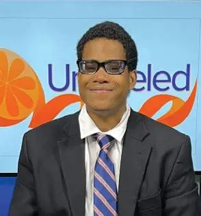 Thomas Wilson wearing a suit and tie, smiling.