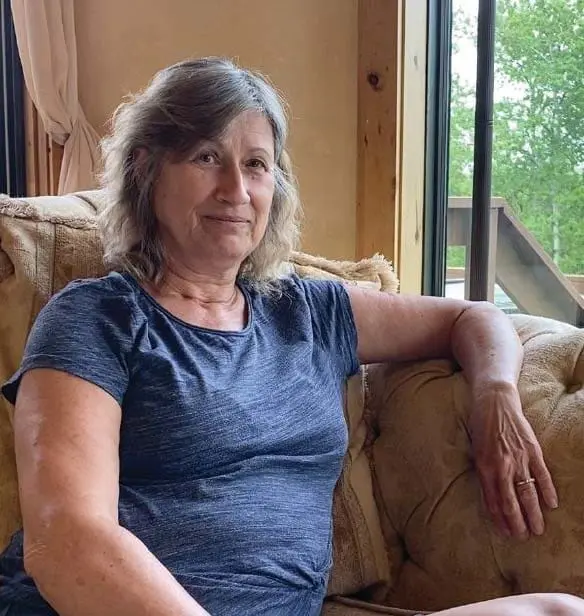 Janice Goll sitting on a couch by a window.