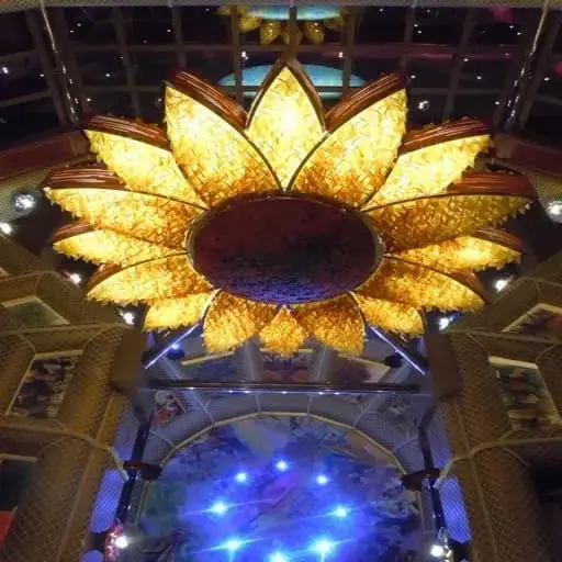 Large illuminated lamp shaped like a sunflower against a dark ceiling.