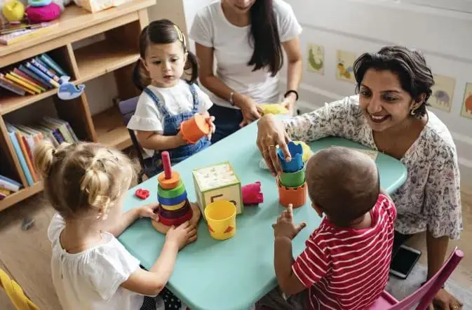 Dr. Cherina Williams playing with children at a table.