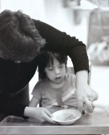 Patricia helping a child eat at a table.