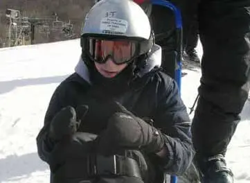 Child in adaptive ski equipment looking forward.