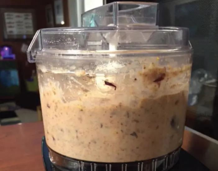 Food processor filled with a light brown, chunky mixture.