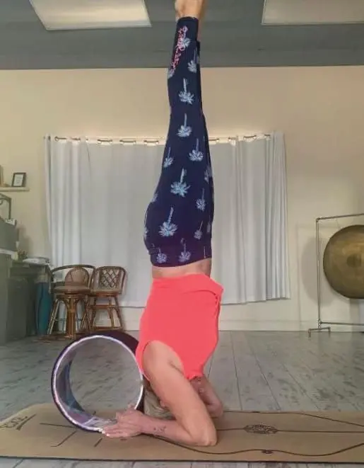 Lisa Lupi performing a headstand with a yoga wheel.
