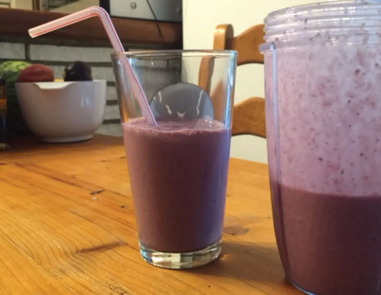 Glass and blender cup filled with purple berry smoothie