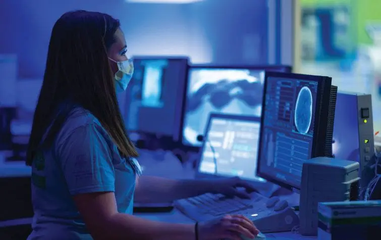 Dr. Susan Apkon in a medical setting reviewing scans on a computer.