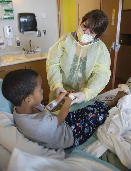 Dr. Susan Apkon tending to a child in a hospital bed.