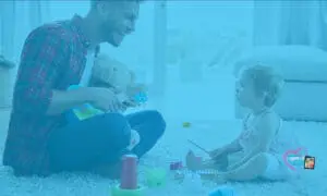 A father and his young child play with toys on the floor.