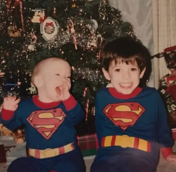 Andrew and Daniel McCoy in Superman costumes by a Christmas tree