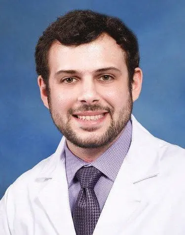 Dr. Andrew McCoy smiling in a white coat.