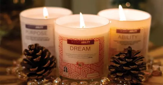Three lit candles labeled "Purpose," "Dream," and "Ability" sit on a decorative surface with pinecones.