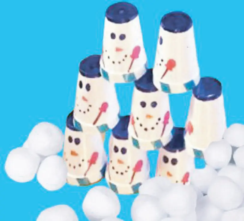 Snowman cups stacked in a pyramid with white snowball-like objects around them.