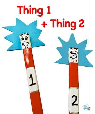 Thing 1 and Thing 2 pencil toppers with blue spiky hair and faces drawn on white labels.