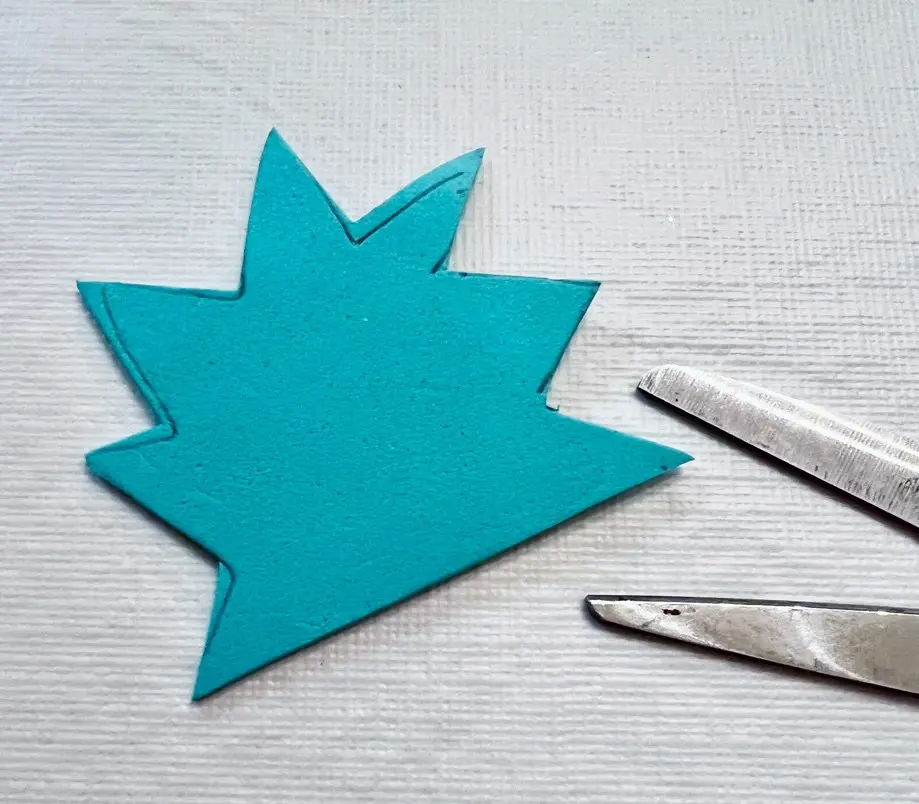 Teal foam zig-zag shape next to two silver scissors.