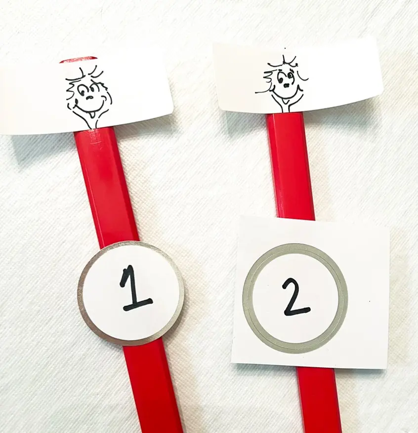 Two red pencils topped with Thing 1 and Thing 2 faces and numbers.
