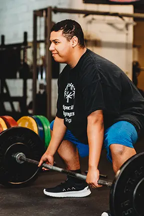 Gabriel preparing to lift a barbell in a gym.