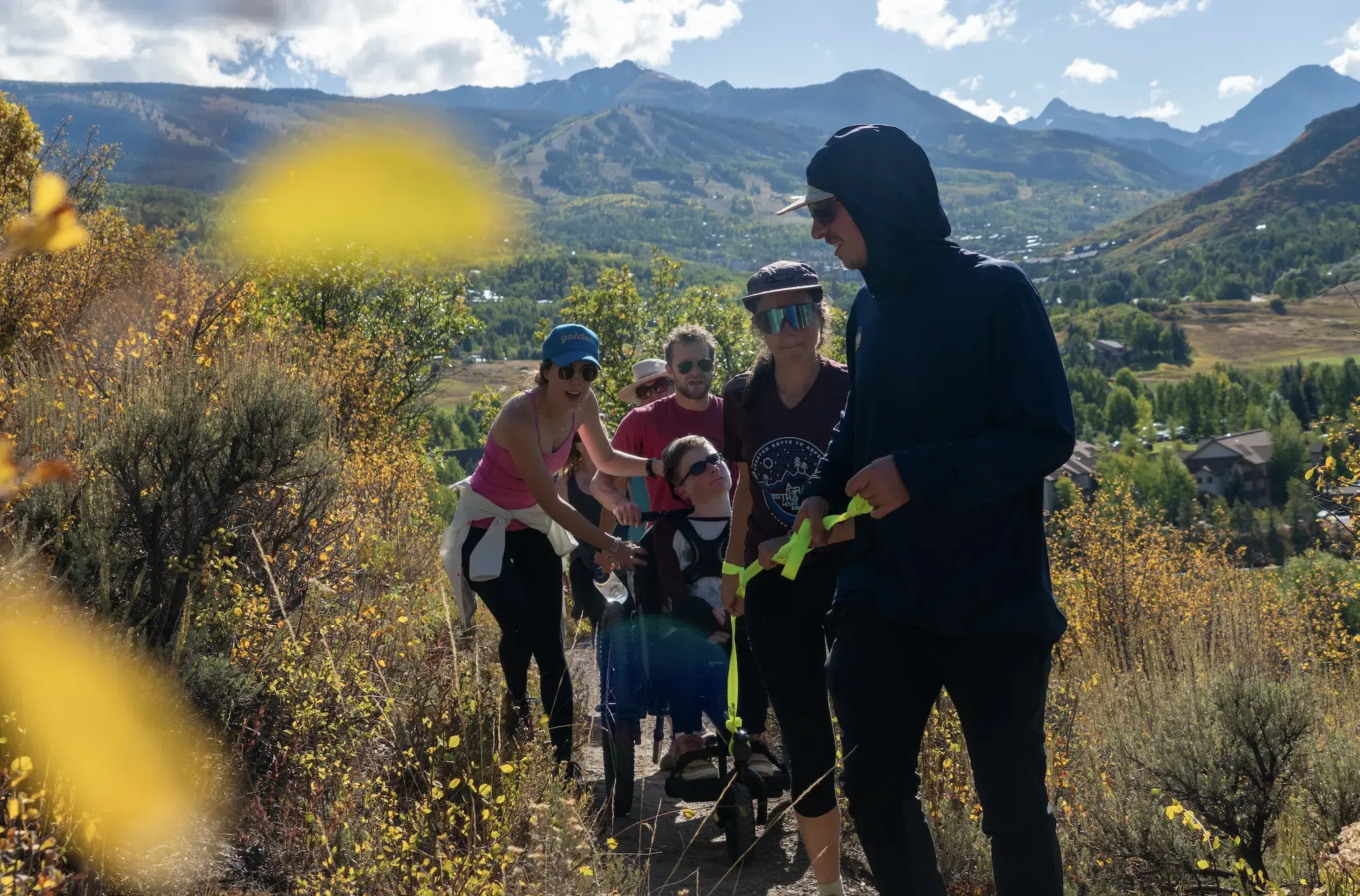 A group of people hikes on a trail with mountains in the background.