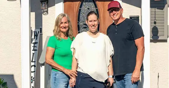 Amanda with two people in front of a house.