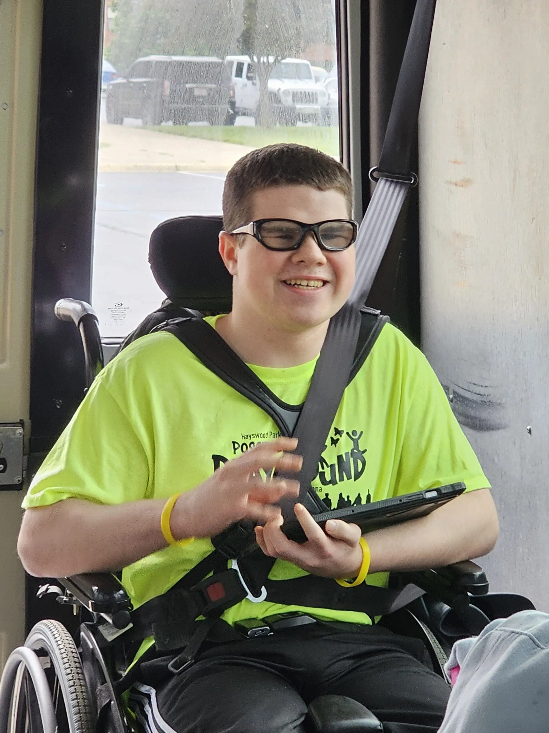 Max smiles while holding a tablet in his wheelchair.