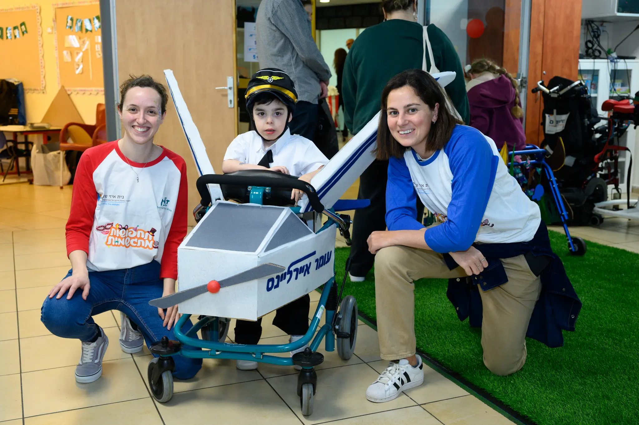 Two women and a child in an airplane-themed costume that attaches to a mobility device.