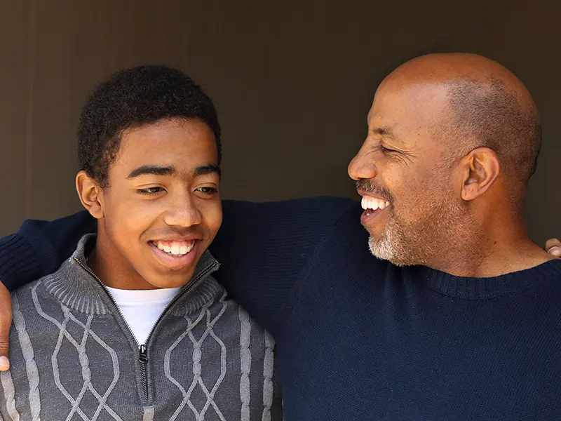 Man and a younger person smiling together.