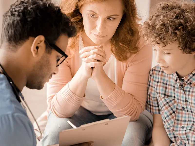 Doctor, woman, and child look at a clipboard.