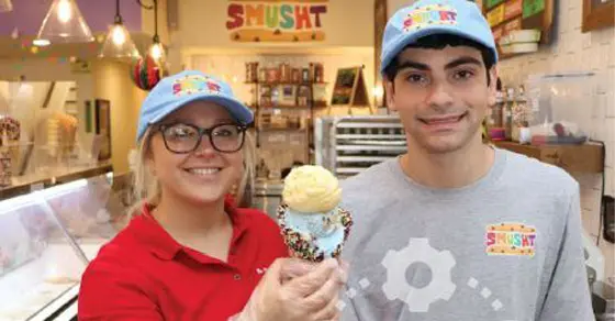 Norma Jean Miller and a co-worker smile holding an ice cream cone in front of a store.