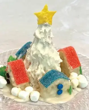 Miniature edible village with a white frosted tree and candy houses.