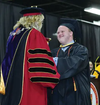 Nicholas McGee smiles as he receives his diploma at graduation.