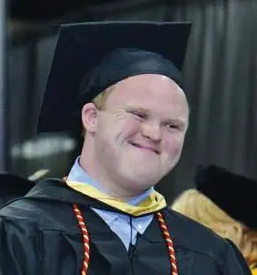 Nicholas McGee smiling while wearing a graduation cap and gown.