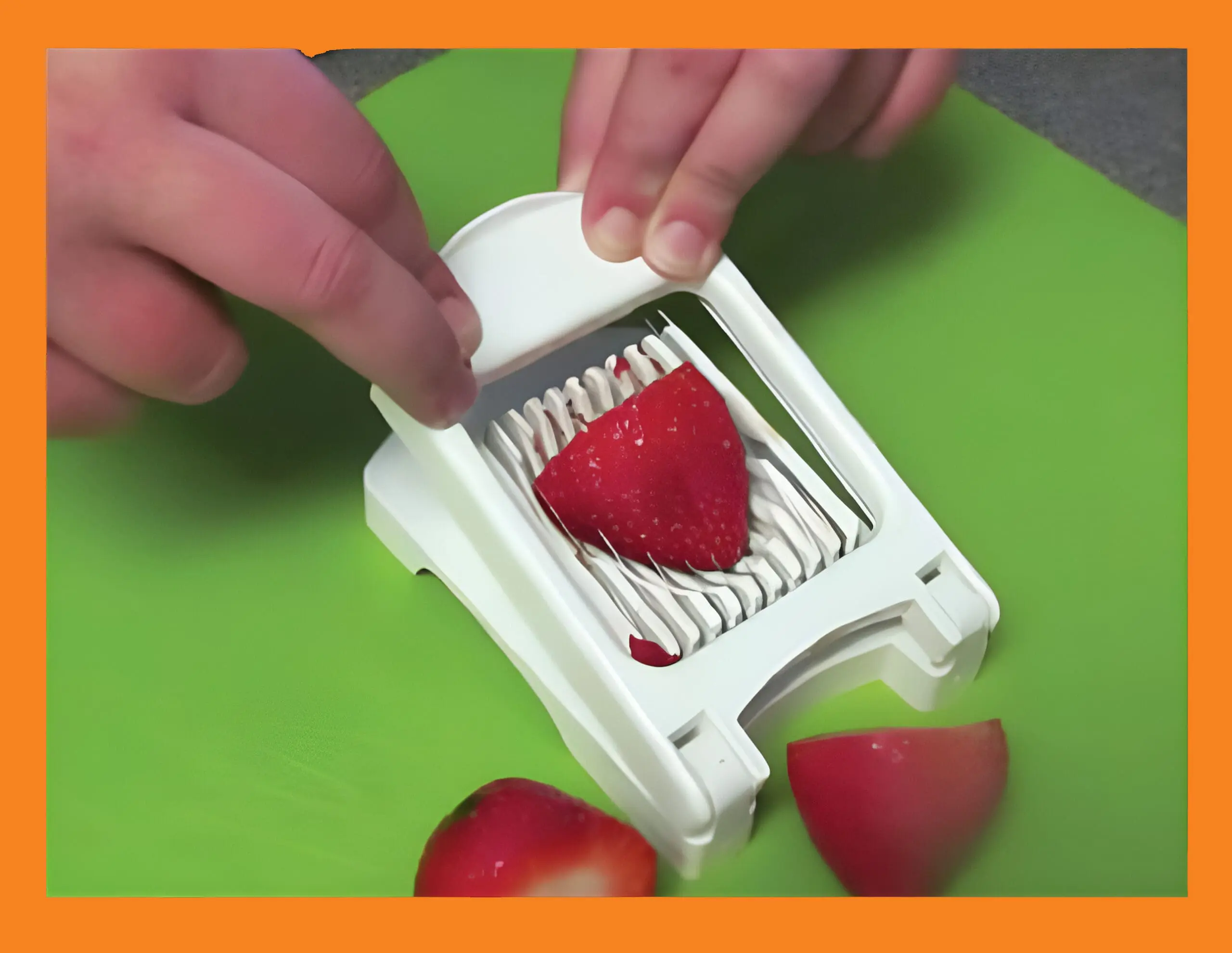 Hands using an egg slicer to cut a strawberry over a green cutting board.
